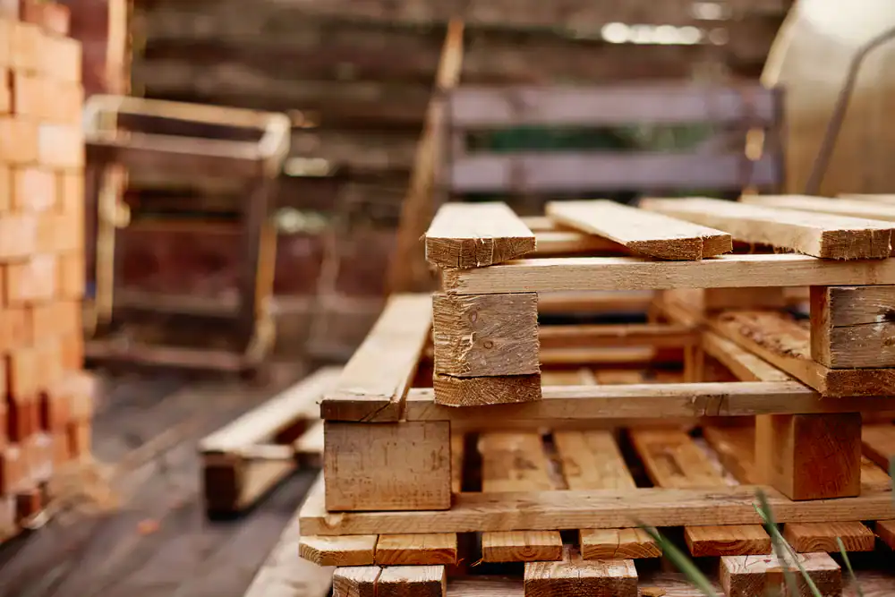 Stacked wooden pallets in a rustic warehouse setting, ready for shipping or storage.